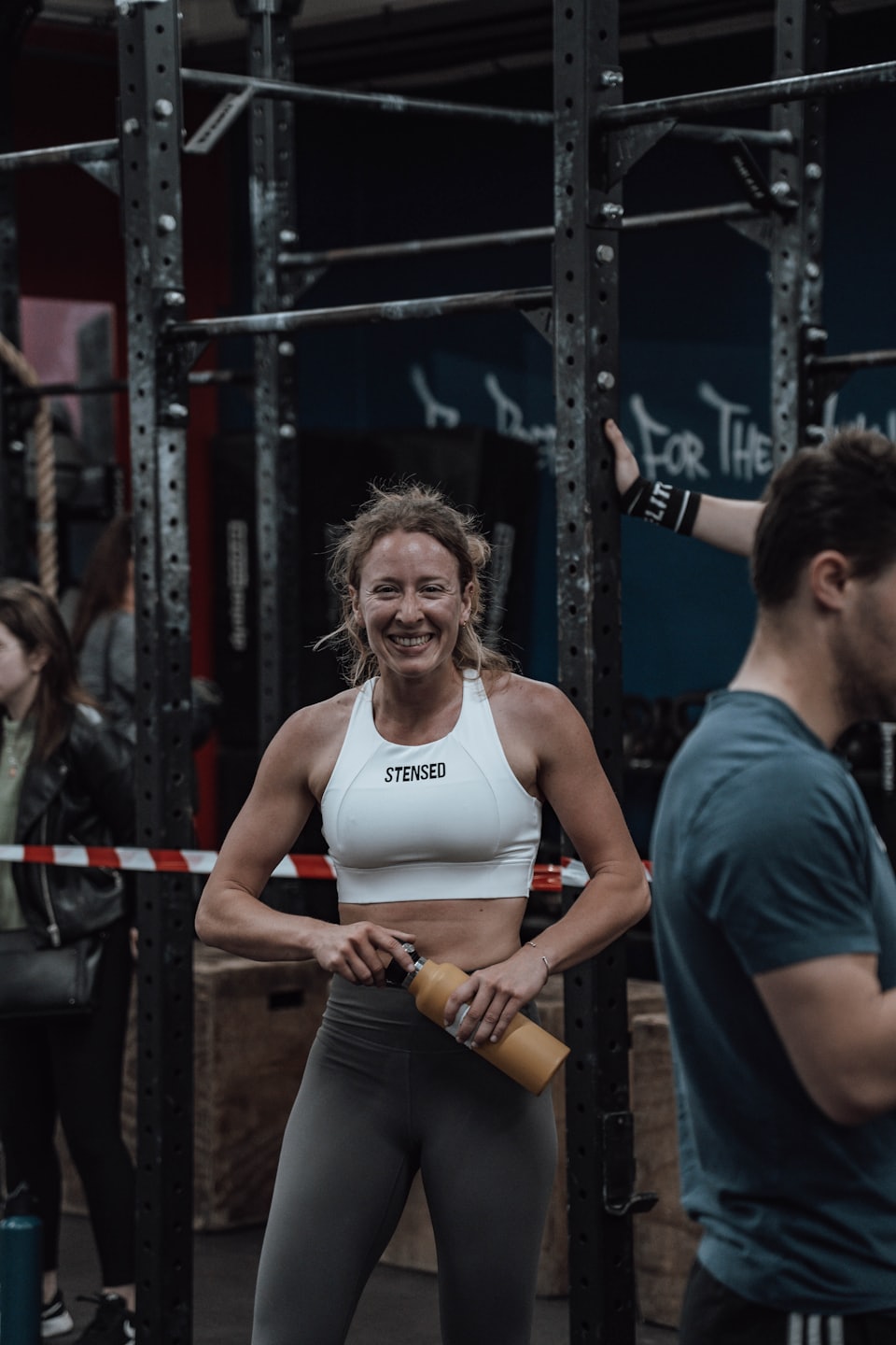 Woman in athletic wear holds a yellow water bottle in a gym.