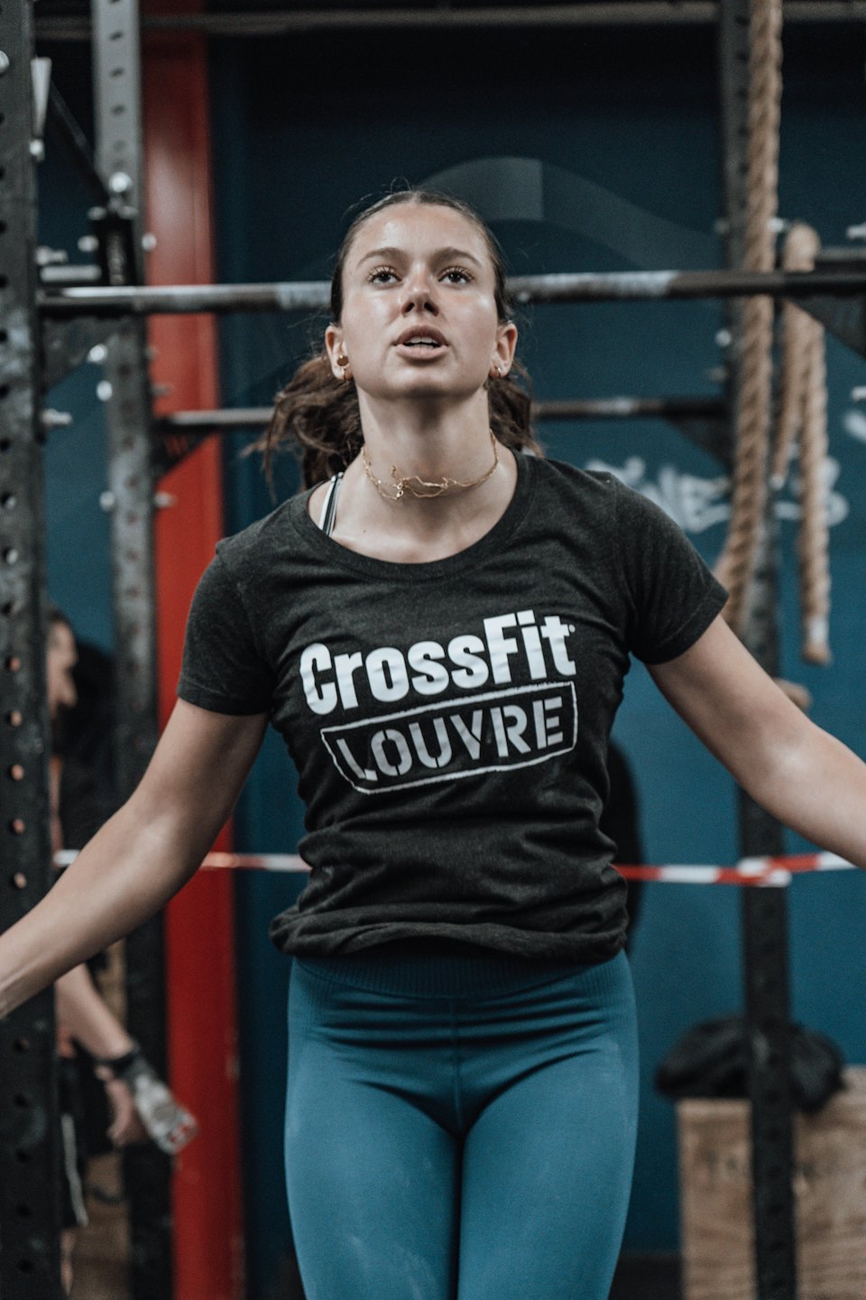 Woman in athletic gear exercises inside a gym.