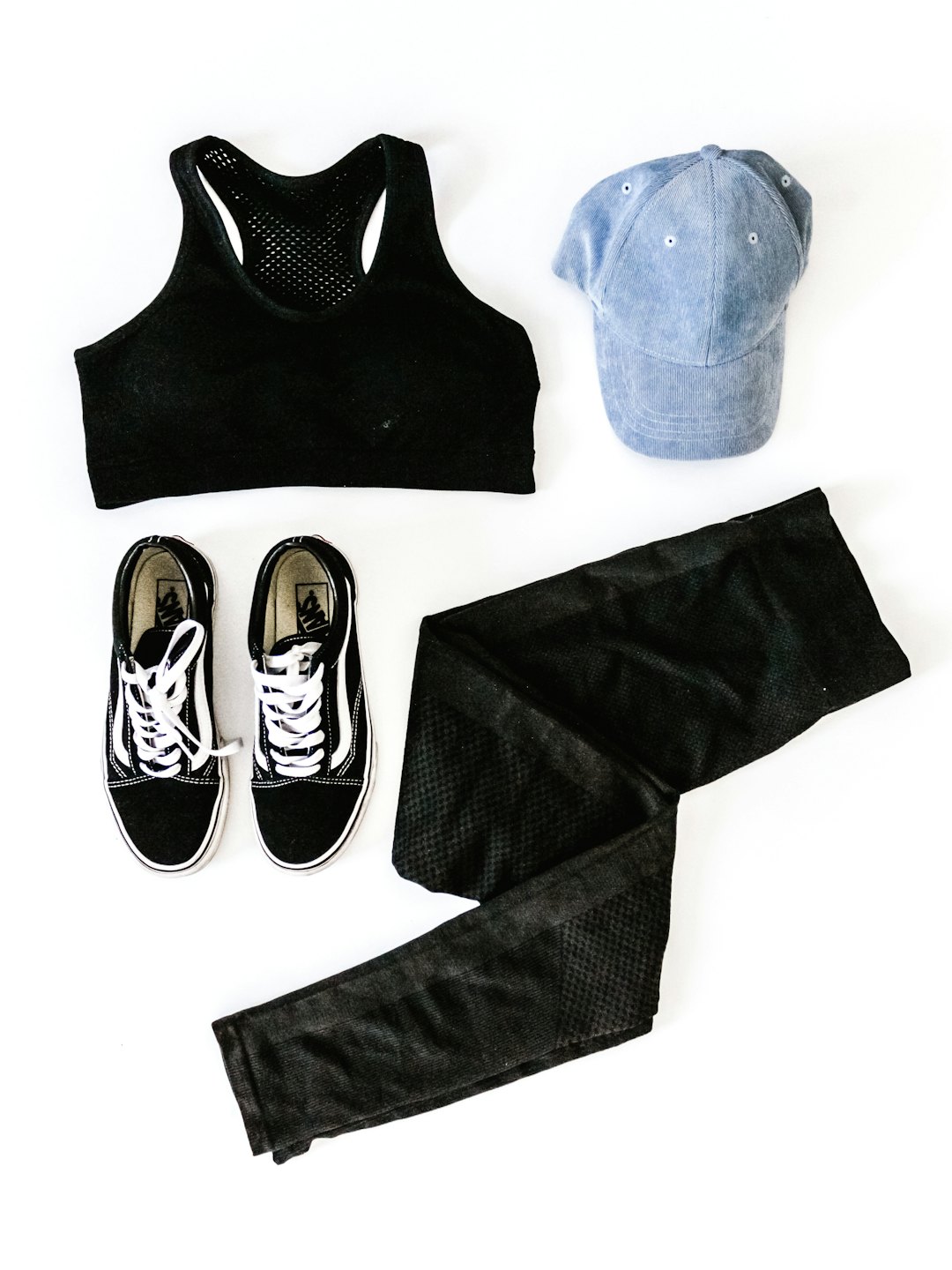 A black athletic outfit and accessories arranged on white.